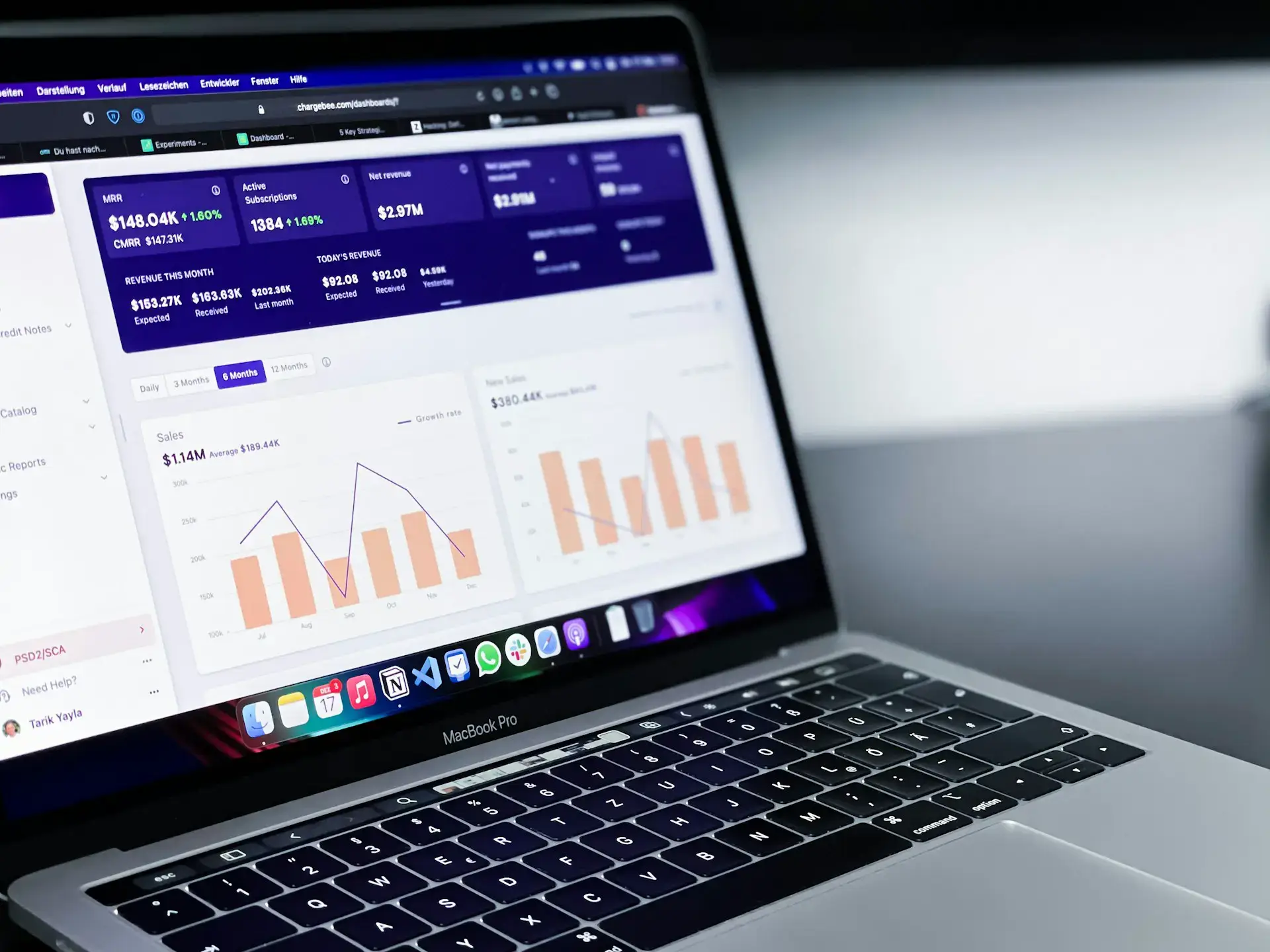 A MacBook Pro displaying data analytics on its screen. The interface shows graphs, statistics, and charts with a dark-themed background. The keyboard is visible, and the surroundings are dimly lit, focusing on the screens content.